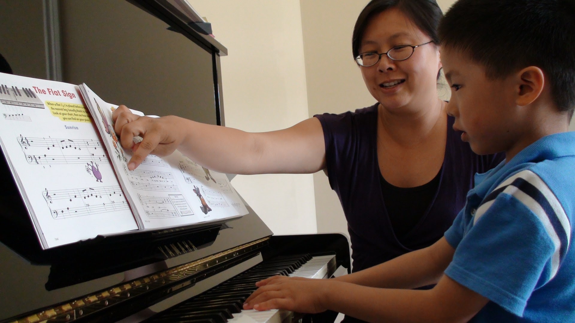 A young beginner student following along at the piano during a lesson with Theresa